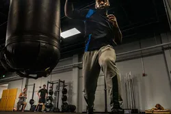 A Man Strongly Kicking a Punching Bag